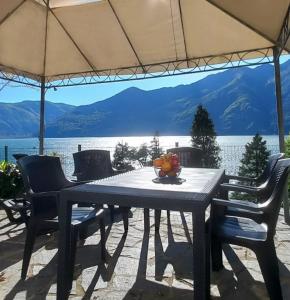 - une table avec des chaises et un parasol avec vue sur le lac dans l'établissement Casa le Palme, à Pino Lago Maggiore