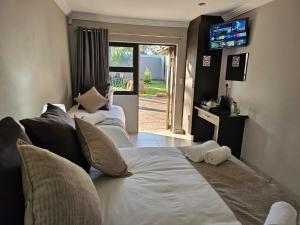 a living room with three beds and a television at Palmera Guest House in Krugersdorp