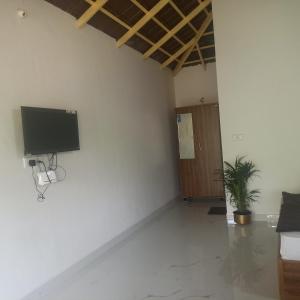 a room with a flat screen tv on a wall at Coffee Country Homestay in Chikmagalūr