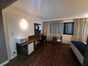 Habitación de hotel con cama, escritorio y TV. en Flat Hotel Internacional Ibirapuera 2534 en São Paulo