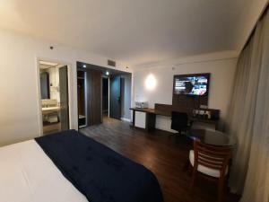 Pokój hotelowy z łóżkiem, biurkiem i telewizorem w obiekcie Flat Hotel Internacional Ibirapuera 2534 w São Paulo