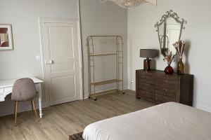 a bedroom with a bed and a desk and a mirror at Le cocon du Faubourg in Vendôme