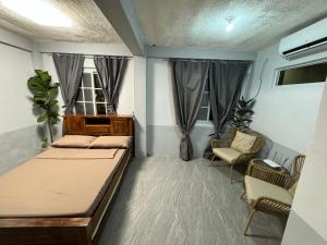 a bedroom with a bed and a chair and windows at The SD Apartment in Camiling