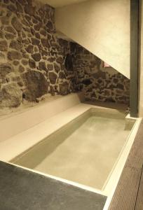 uma banheira num quarto com uma parede de pedra em El jazmín de la Fuente casa rural em Guijo de Santa Bárbara