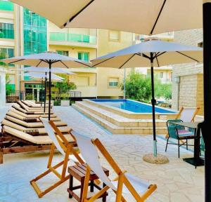 a group of chairs and umbrellas next to a pool at Apartment Becici in Becici