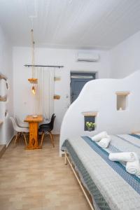 a white bedroom with two beds and a table at Feel the Serenity 2 in Galini