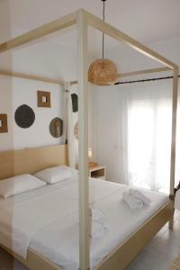 - une chambre avec un lit à baldaquin et des draps blancs dans l'établissement Arco In Pietra, à Apolakkiá