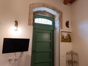 a green door in a room with a tv at Casetta Santa Venera in Modica