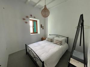 a bedroom with a bed with white sheets and a mirror at Tinos Traditional Patio House in Arnados