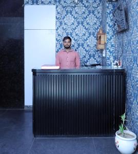 新德里的住宿－Nidra Hotel，站在厨房柜台后面的人
