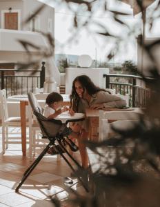 Elea Suites & Residences في غوفي: وجود امرأة وطفل يجلسون على طاولة