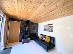a living room with a black couch and a wooden ceiling at Hunters Hideaway-Hot Tub-Wiltshire-Groups in Warminster