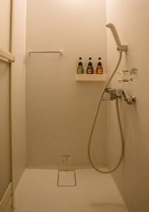 um chuveiro numa casa de banho com duas garrafas numa prateleira em Kominka Guesthouse SENTŌ em Yakumo