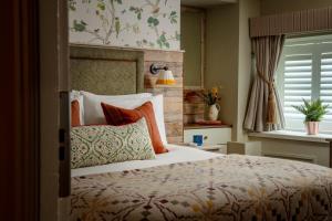 een slaapkamer met een groot bed met kleurrijke kussens bij The Golden Lion at Settle in Settle