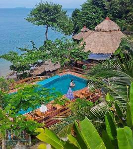 una persona de pie junto a una piscina junto al océano en Koh Jum Resort, en Ko Jum