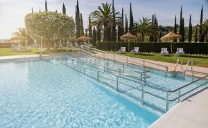 una gran piscina de agua azul en un complejo en Ilunion Alcora Sevilla en San Juan de Aznalfarache