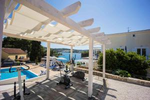 uma vista para uma piscina com uma pérgola branca em Boutique Guesthouse Sveti Petar, on the beach, heated pool, restaurant & boat berth - ADULT ONLY em Necujam