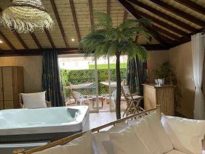 a living room with a tub and a palm tree at La Ferme Briarde in Couperdrix