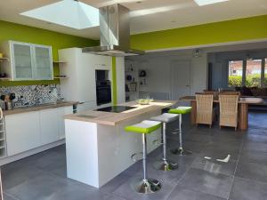 a kitchen with white cabinets and green walls at Maison THEB in Saint-André-lez-Lille +3 photos