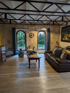 uma sala de estar com um sofá de couro e uma mesa em Warm 2 bedroom stone house with garden - Dodo et Tartine em Saint-Sigismond
