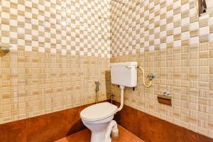 a bathroom with a toilet in a tiled wall at FabHotel Peak Stay in Porvorim