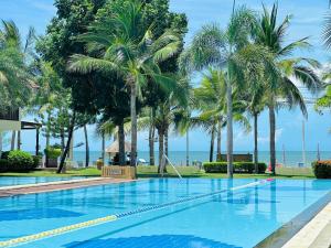 a swimming pool with palm trees and the ocean at Dolphin Bay Beach Resort in Sam Roi Yot