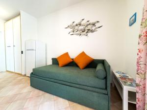 a living room with a green couch with orange pillows at Appartamento Stefania Località Nisportino in Rio nellʼElba