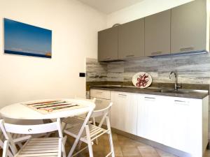 a kitchen with white cabinets and a white table and chairs at Appartamento Stefania Località Nisportino in Rio nellʼElba