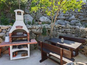 uma grelha ao lado de uma mesa de piquenique e um banco em House Kaja em Jablanac