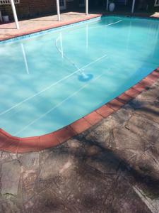 an empty swimming pool with a tennis court at Comrades Oasis Guest House in Pietermaritzburg