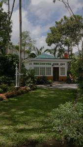 a white house with a green roof and a yard at Kallista Villa Kalibaru in Kalibaru