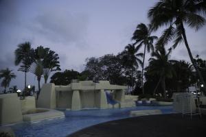 a resort pool with a slide and palm trees at Heden Golf Hotel in Abidjan