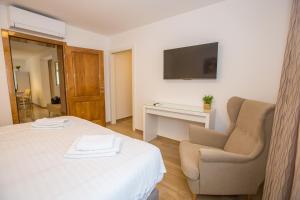 a bedroom with a bed and a chair and a television at Apartment Riva Parenzo in Poreč