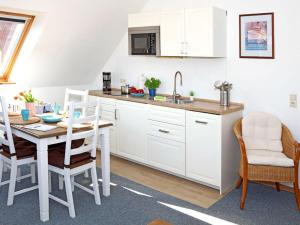 a kitchen with white cabinets and a table and chairs at House in Legde "East" in Norderney +7 photos