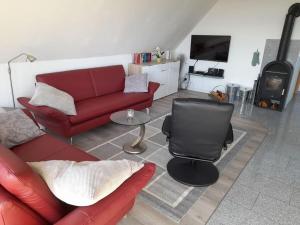 a living room with a red couch and a red chair at Nordseeoase Pethan 2 - Boven in Neuharlingersiel