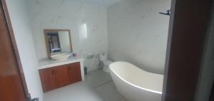 a white bathroom with a tub and a sink at Tebanyoman Guesthouse in Dalung