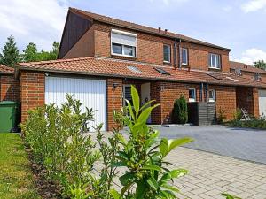 a brick house with two white garage doors at Holiday home Heide Comfortable holiday residence in Bad Fallingbostel