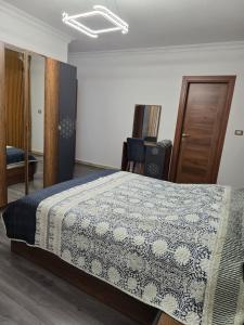 1 dormitorio con 1 cama con manta azul y blanca en El-Shaikh Zayed, 6 october 3BHK flat- families only en Sheikh Zayed