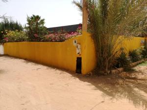 una valla amarilla con flores al costado de una carretera en Villa Ty an heol, en Ngaparou