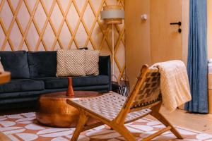 a living room with a black couch and a chair at Dacza Puchacza Glamping in Stare Osieczno