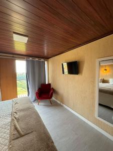 パティ・ド・アルフェレスにあるPousada Recanto Querubinsのベッドルーム1室(ベッド1台、赤い椅子付)