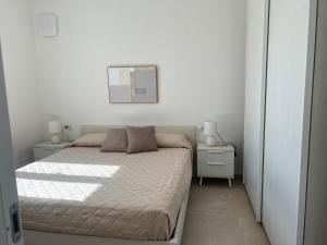 ein weißes Schlafzimmer mit einem Bett und zwei Nachttischen in der Unterkunft La Casa di Spinosella in Valledoria
