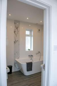 ein weißes Bad mit einer Badewanne und einem Fenster in der Unterkunft Stylish Retreat in Leigh-on-Sea in Southend-on-Sea