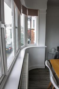 Cette chambre dispose de grandes fenêtres, d'une table et de chaises. dans l'établissement Stylish Retreat in Leigh-on-Sea, à Southend-on-Sea