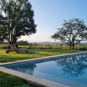 a swimming pool in a field with a bench and trees at Aux ducs de Sienne in Montagne