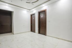 an empty room with three doors and a tile floor at FabHotel JP Villa in Varanasi