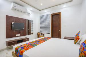 FabHotel JP Villa في فاراناسي: غرفة نوم بسرير وتلفزيون بشاشة مسطحة