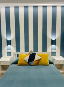 1 cama con almohadas amarillas y rayas azules y blancas en La Titina Sella en Bari