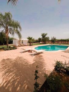 una piscina con 2 tumbonas y una mesa en Villa privée Wafa en Marrakech