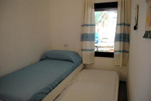 a small bedroom with a bed and a window at Cala Sinzias beach house with stunning views in Costa Rei